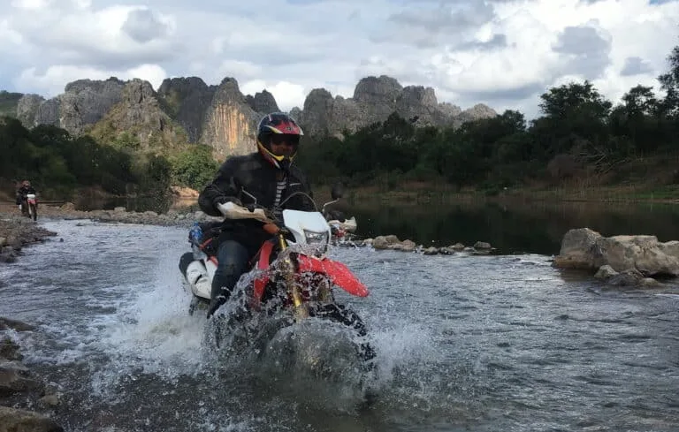 An Explore Indochina rider crossing a stream near Mahaxai while riding the Ho Chi Minh Trail